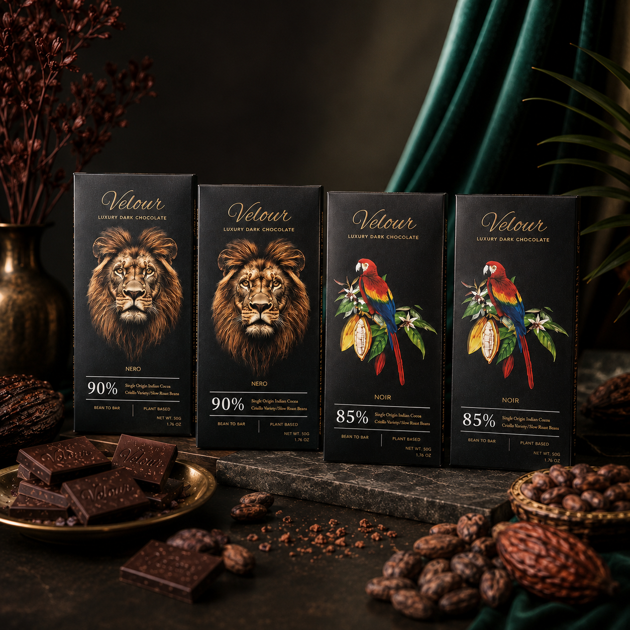 Four black chocolate bars from the brand Vélour are displayed on a dark stone surface with chocolate pieces scattered around. The packaging features artistic illustrations of a lion, two parrots, and a toucan, with dark chocolate pieces and cacao beans used as styling props against a dark, moody background with green drapery.