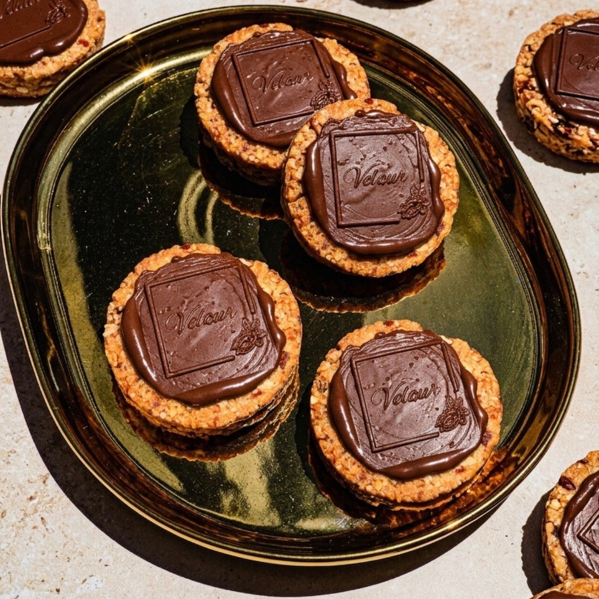 Chocolate-topped cookies on a gold tray with a light background